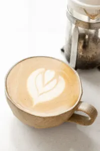A stoneware mug with a latte with latte art.