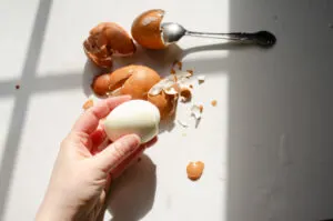 A hand holding a peeled hard boiled egg.