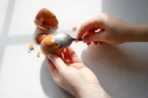 Using a spoon to help peel a hard boiled egg.