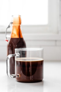 A mug of coffee with chocolate syrup in the background.