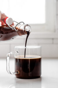 Pouring chocolate syrup into a mug of coffee.