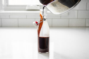 Pouring the chocolate syrup for coffee into a bottle for storage.