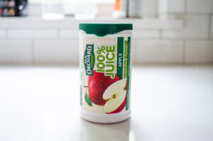 A container of frozen apple juice concentrate on a white countertop.