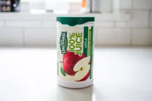 A container of frozen apple juice concentrate on a white countertop.