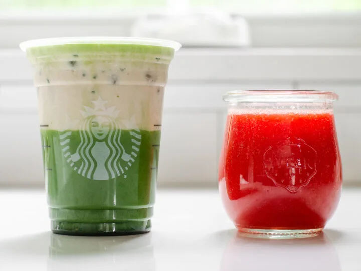 A jar of homemade Starbucks strawberry puree sauce next to a Starbucks glass filled with an iced matcha latte and strawberry cold foam on top.