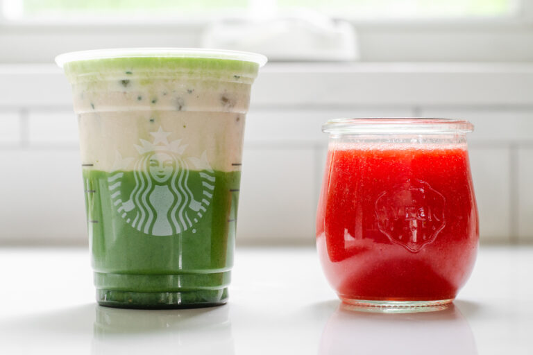 A jar of homemade Starbucks strawberry puree sauce next to a Starbucks glass filled with an iced matcha latte and strawberry cold foam on top.