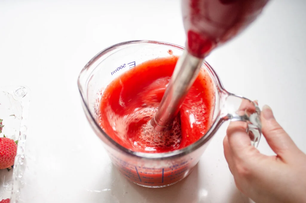 Pureeing strawberries with an immersion blender.