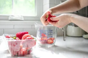 Slicing the strawberries in half before measuring them.