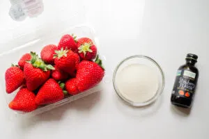 All of the ingredients needed to recreate the Starbucks strawberry puree laid out on a white countertop.