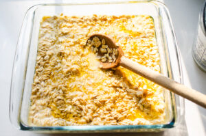 Mixing the baked oatmeal batter in with the melted butter in the pan.