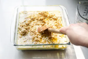 Mixing the baked oatmeal batter in with the melted butter in the pan.