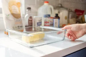 Placing a stick of butter in a square glass baking dish.