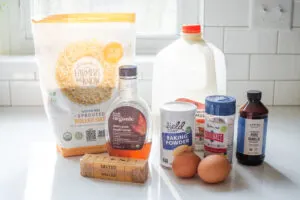 All of the ingredients needed to make baked oatmeal laid out on a white countertop with a window in the background.