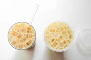 A side by side top down picture of a homemade iced vanilla latte and a coffee shop version.