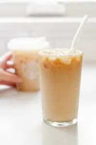 A copycat Starbucks iced vanilla latte with the original Starbucks version in the background.