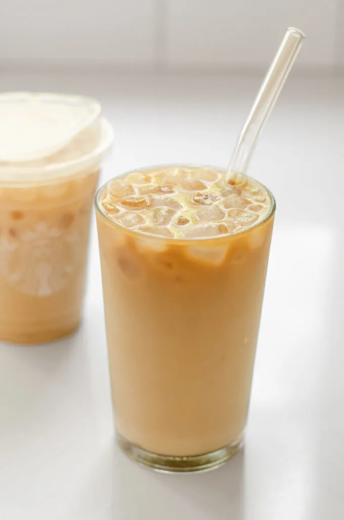 A copycat Starbucks iced vanilla latte with the original Starbucks version in the background.