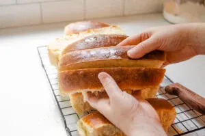 Slicing the homemade hotdog bun down the middle, or vertically. 