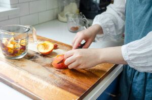 Dicing fresh peaches on a wooden cutting board.