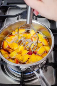 Mashing the peaches with a mini potato masher.