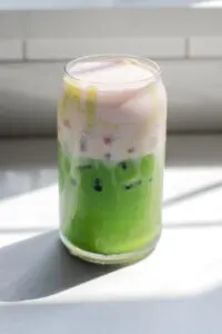 A copycat Starbucks iced matcha latte with strawberry sweet cream on top.