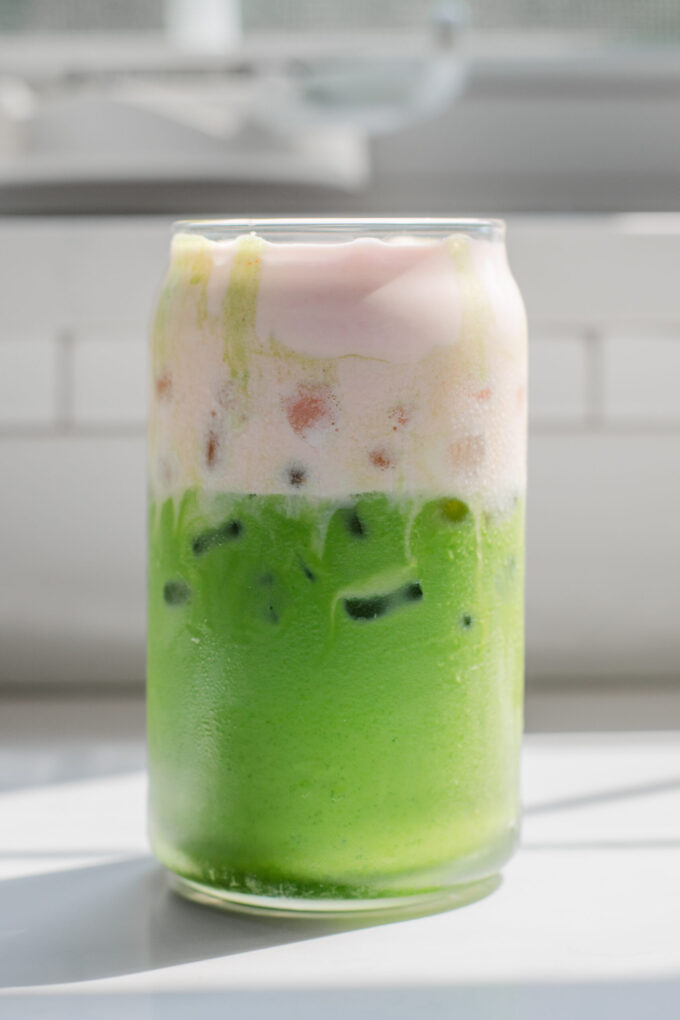 A copycat Starbucks iced matcha latte with strawberry sweet cream on top.
