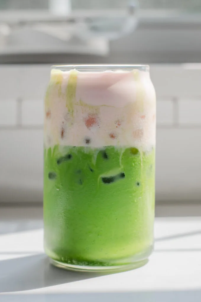 A copycat Starbucks iced matcha latte with strawberry sweet cream on top.