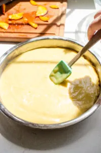 Smoothing the cake batter on top of the peaches in the pan.