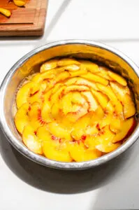 Peach slices arranged like a flower on the bottom of the cake pan.