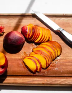 Peach slices on a wooden cutting board.