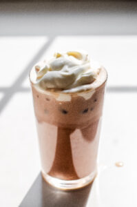 A glass of homemade Starbucks mocha iced latte on a sunny white countertop.