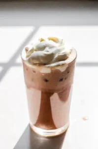 A glass of homemade Starbucks mocha iced latte on a sunny white countertop.