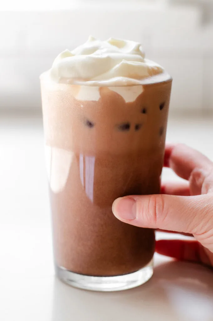 A hand holding a glass of copycat Starbucks iced caffe mocha.