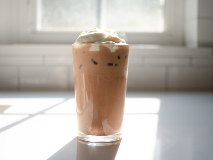 A glass of homemade Starbucks mocha iced latte on a sunny white countertop.