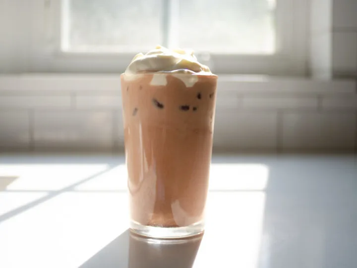 A glass of homemade Starbucks mocha iced latte on a sunny white countertop.