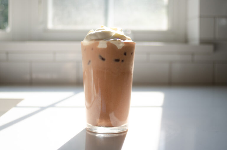A glass of homemade Starbucks mocha iced latte on a sunny white countertop.