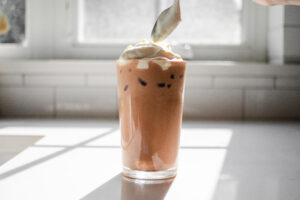 Dolloping the whipped cream on top of the iced mocha.