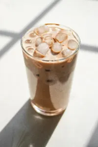 A glass of homemade Starbucks mocha iced latte on a sunny white countertop.