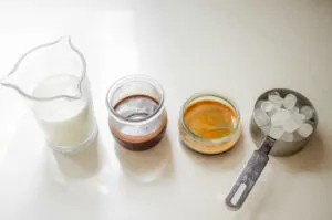 All of the ingredients needed to make a copycat Starbucks mocha iced coffee laid out on a white countertop.