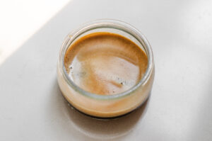 A small jar of espresso on a white countertop.