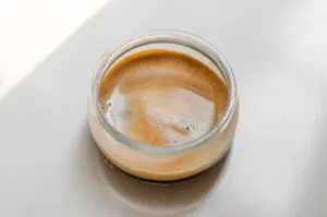 A small jar of espresso on a white countertop.