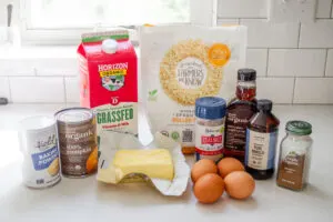 All of the ingredients needed to make pumpkin pie baked oatmeal laid out on a white countertop. 