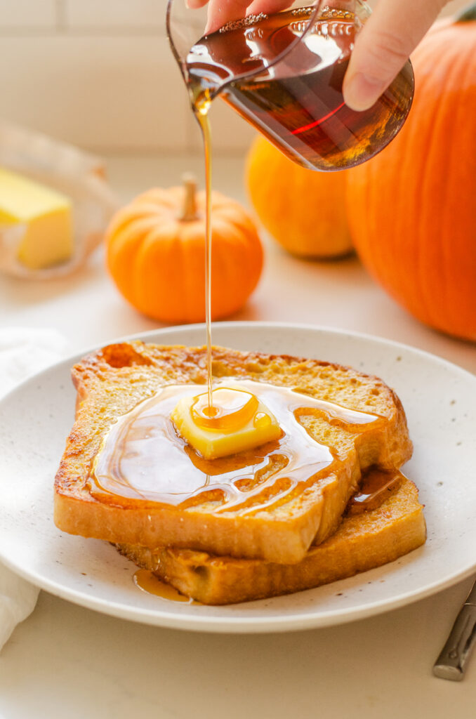 Pouring maple syrup on two slices of Pumpkin French Toast.