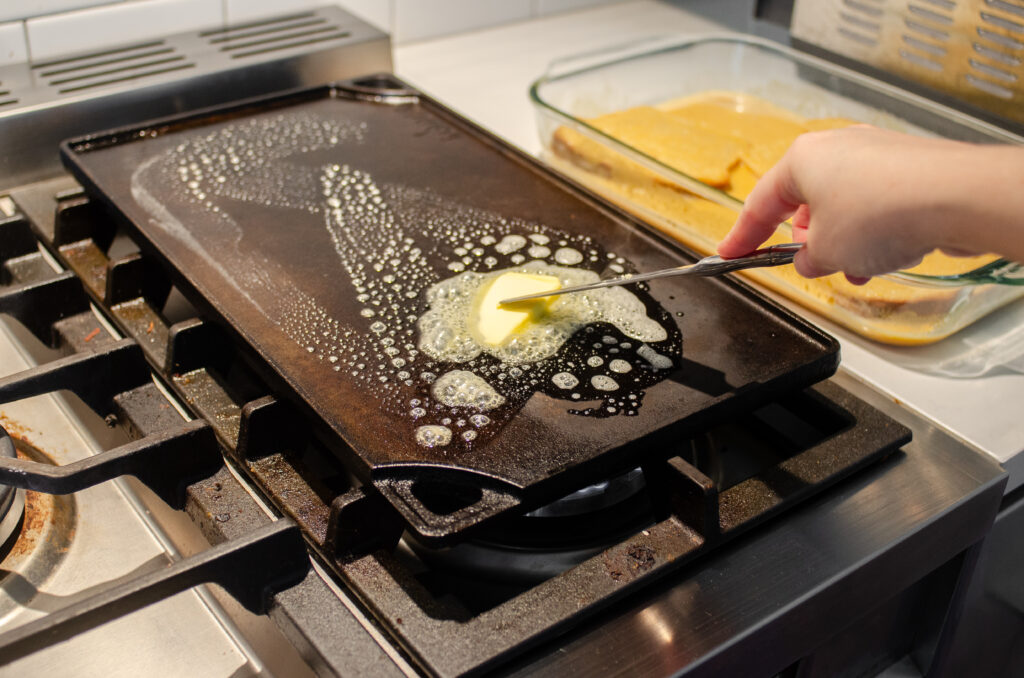 Adding butter to a hot cast iron griddle.