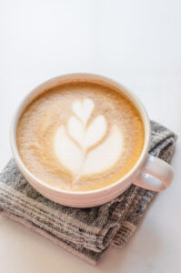 A white mug with a homemade latte on a linen tea towel.
