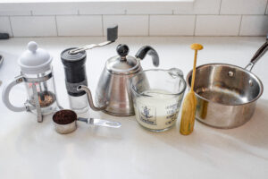 All of the ingredients and equipment needed to make a latte with a french press.