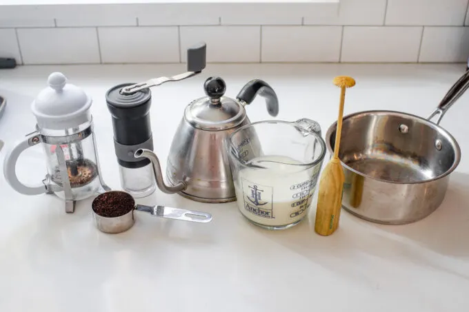All of the ingredients and equipment needed to make a latte with a french press.