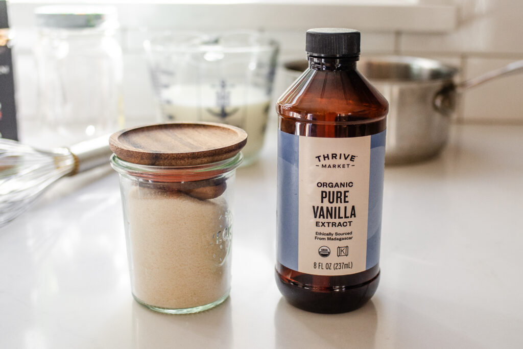 A small jar of sugar with a bottle of vanilla extract next to it.