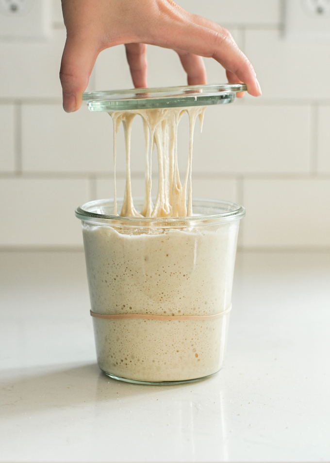 A hand lifting the lid of a Weck jar.