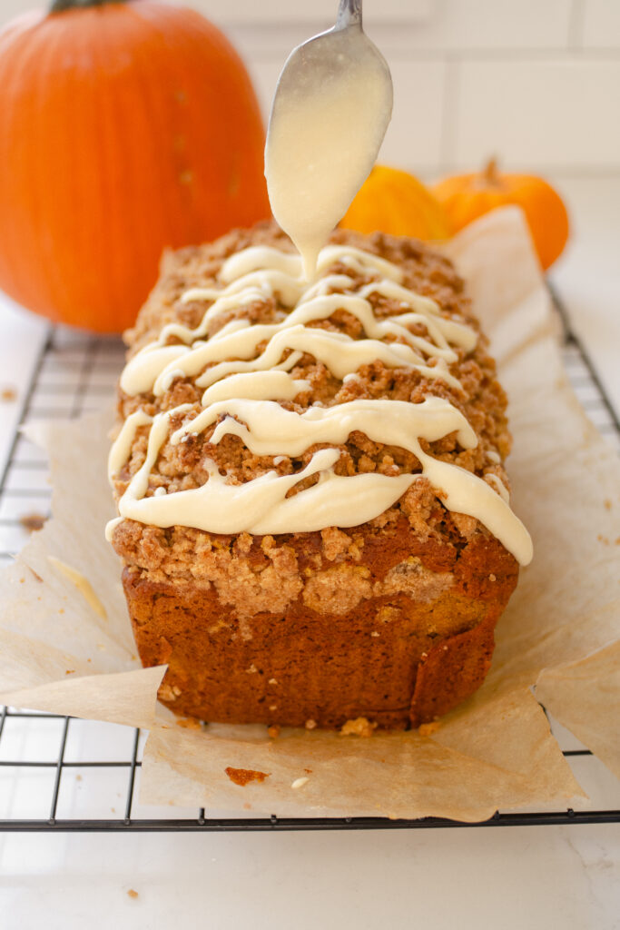 Drizzling the cream cheese glaze on top of the loaf.
