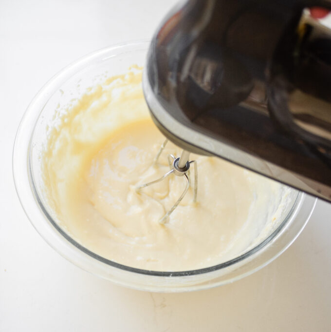 Beating the cream cheese frosting ingredients together.
